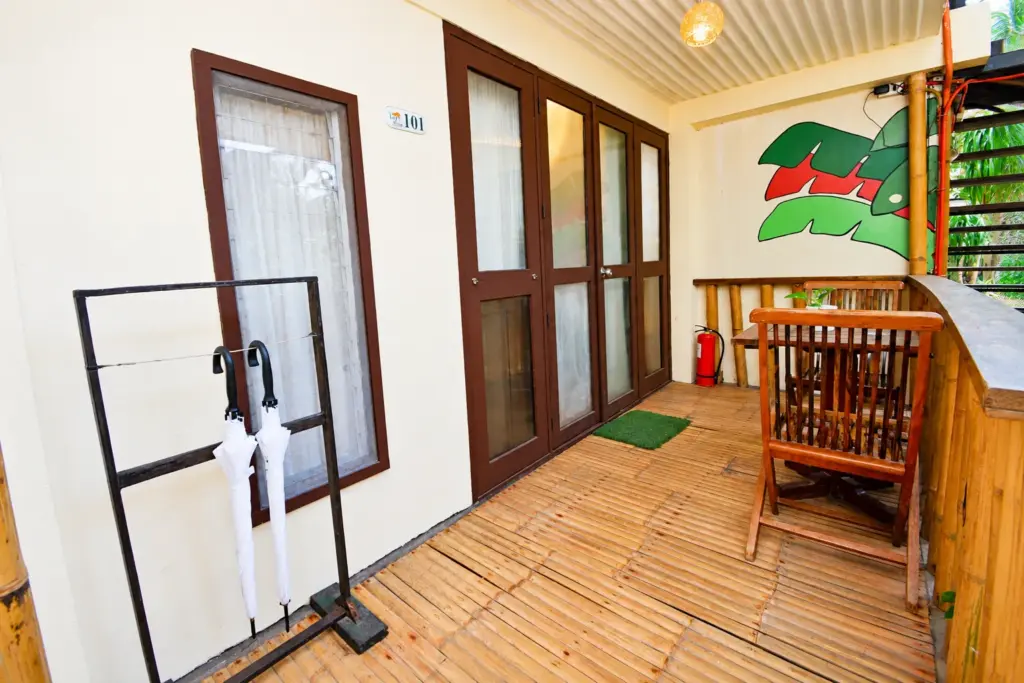 Wooden deck with a chair and umbrella stand beside the glass doors of a Cottage