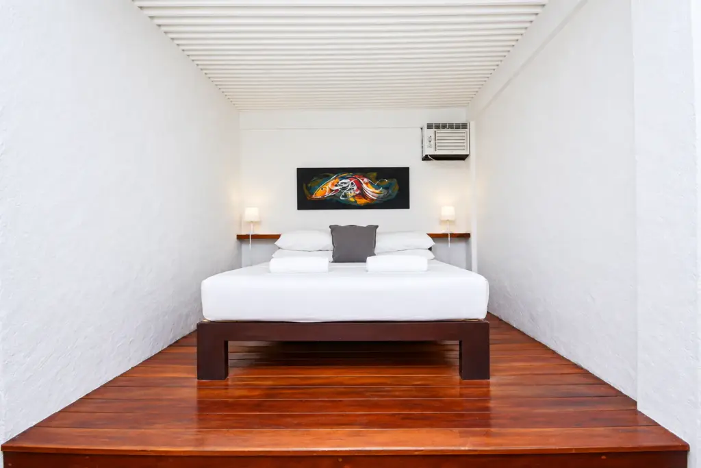 Queen bed on a raised wooden platform with colorful artwork above