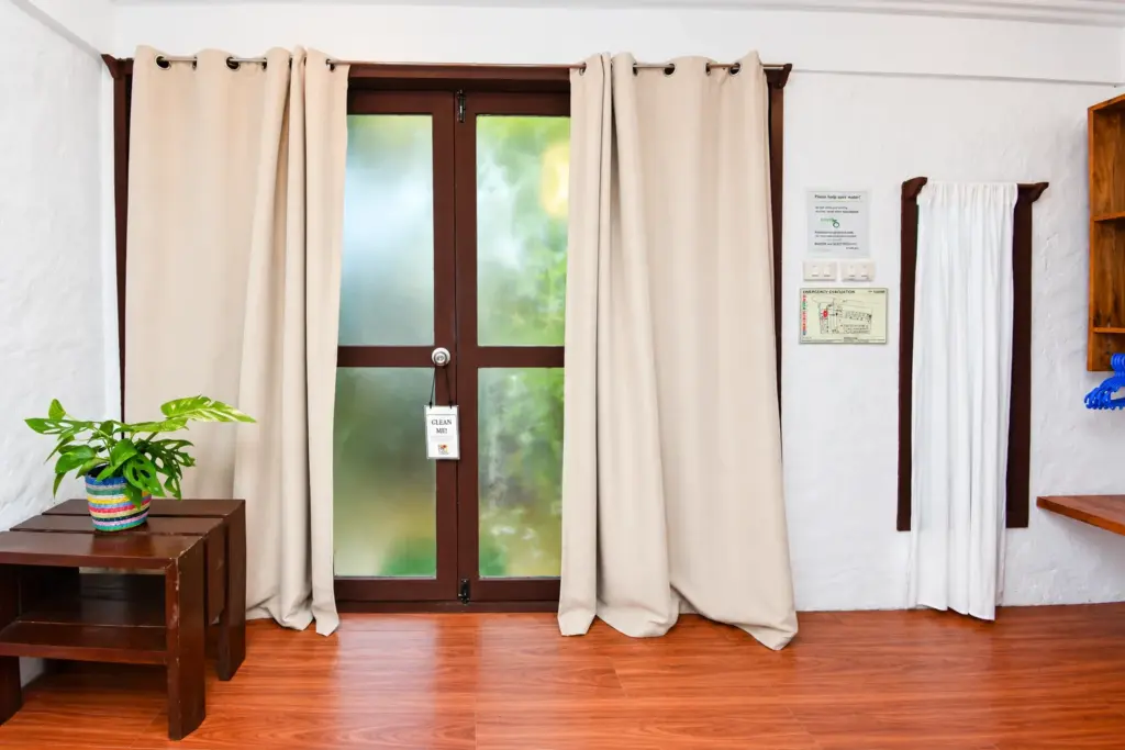 Glass doors with curtains and a plant on a wooden side table