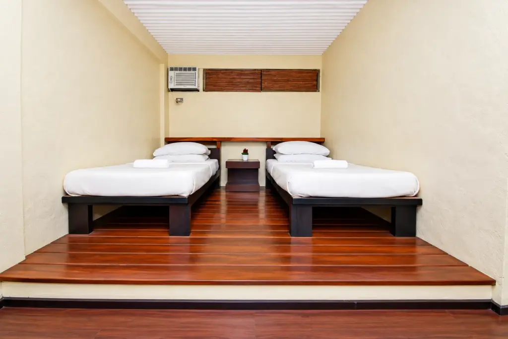 Two single beds with dark wood frames on a raised wooden floor