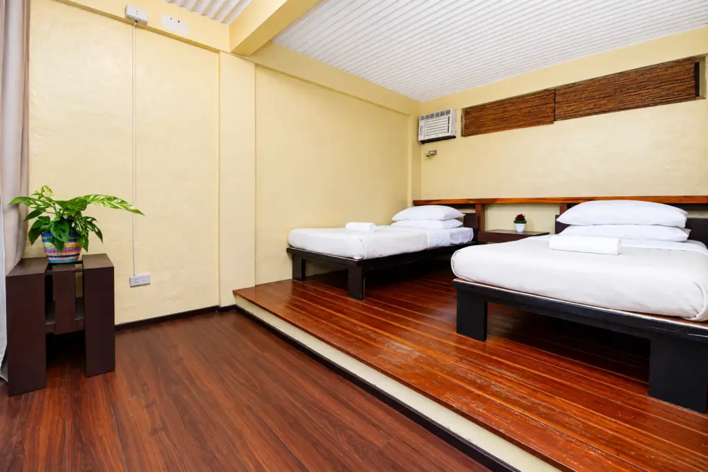Beds on a raised wooden platform with a plant and air-conditioning