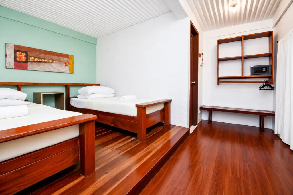 Twin beds with a mint-green wall, open shelving and in-room safe