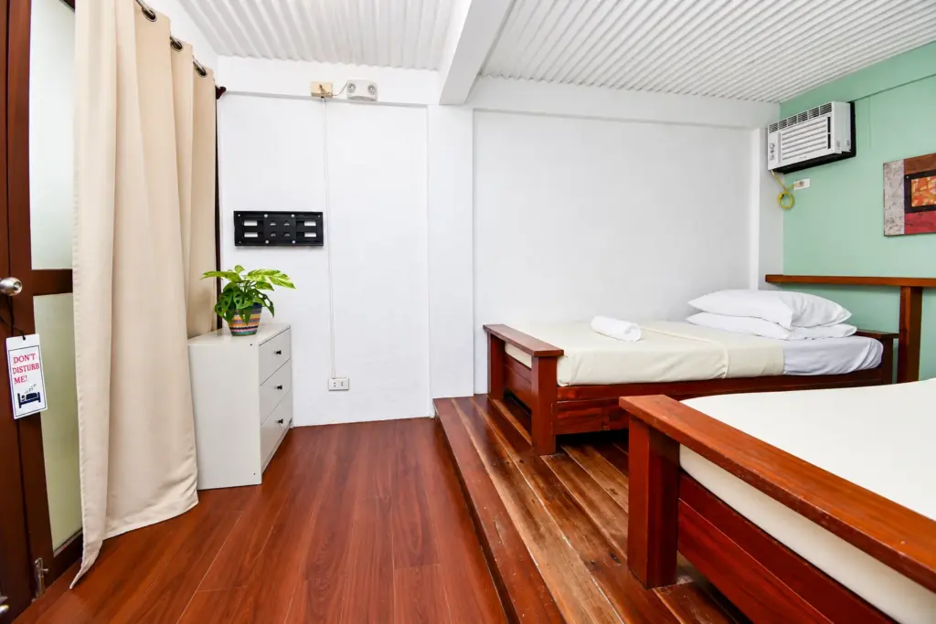 Bed on a wooden floor with curtains and a white dresser