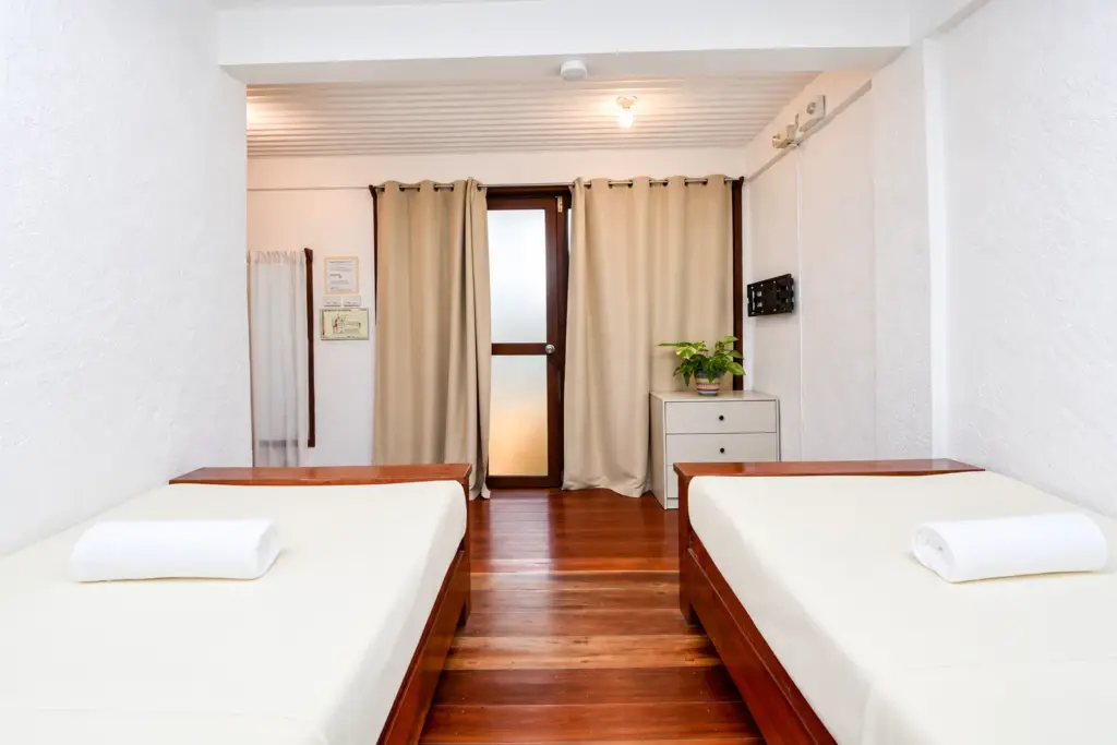 Two single beds with wooden frames facing the glass doors