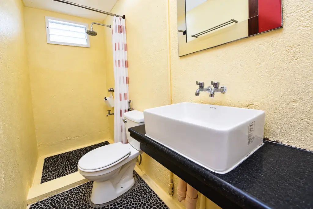 Bathroom with a square white basin and toilet on a pebble floor