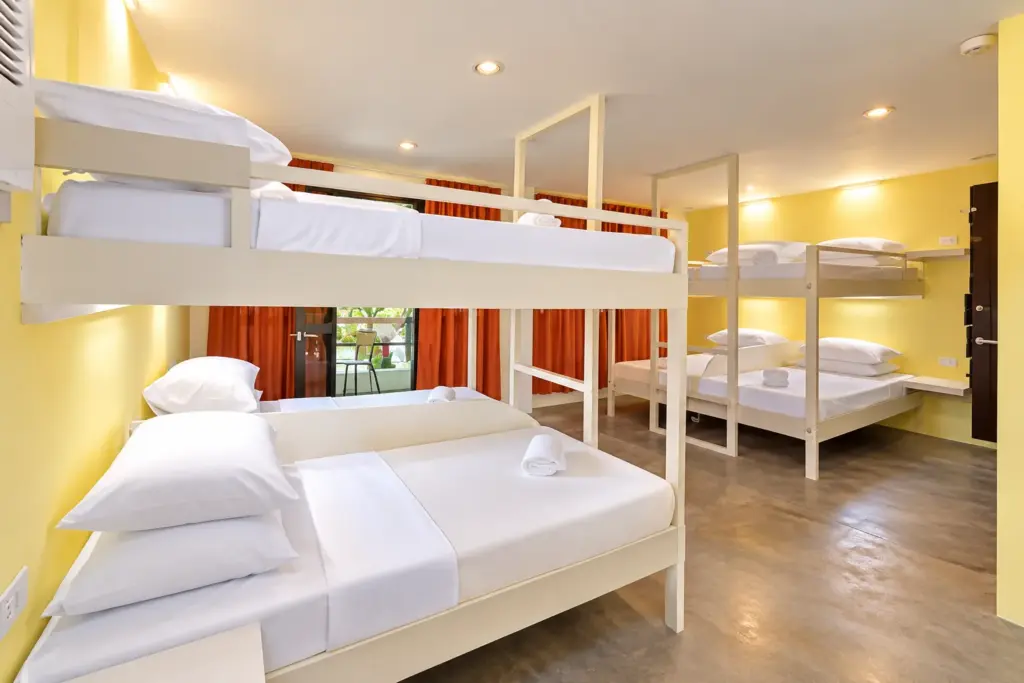 Bunk beds with plump pillows and fresh white linens, with more bunks beyond