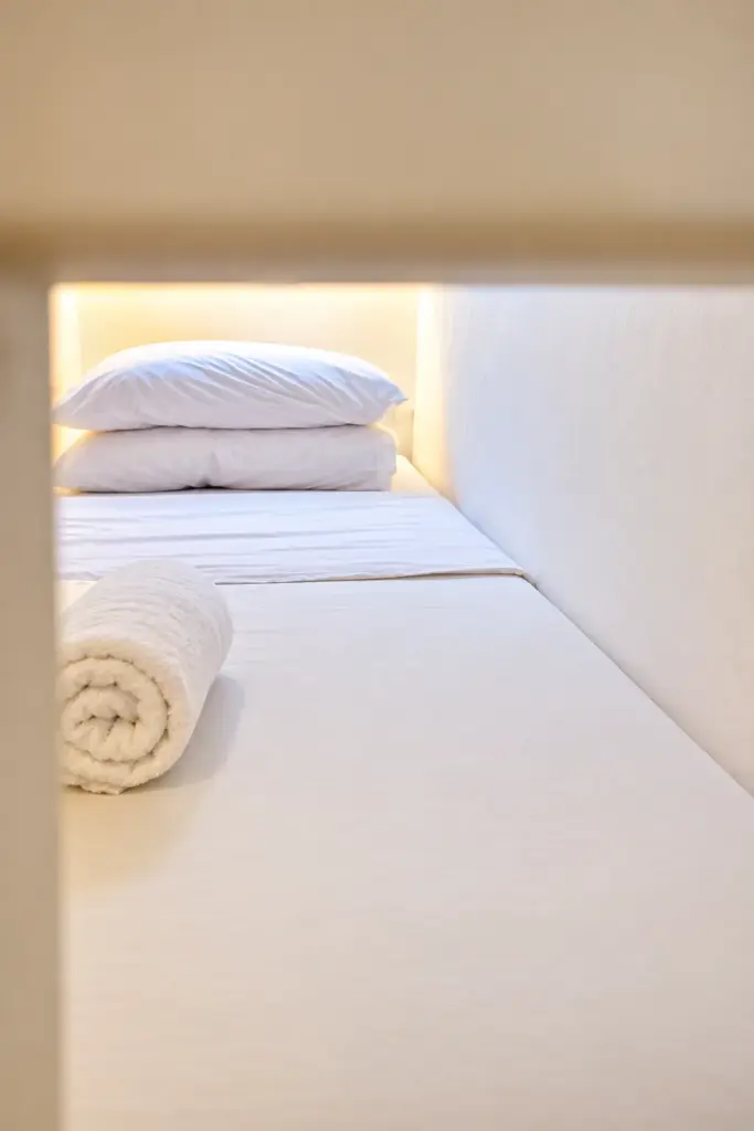 Inside a bunk with a pillow, rolled blanket and built-in light
