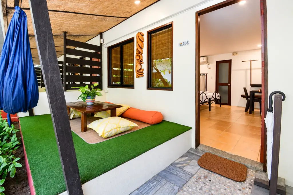 Terrace with hammock and cushions beside the open entrance to the Family Room