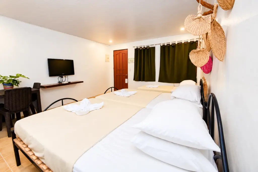 Bed with plump pillows, a desk and green curtains