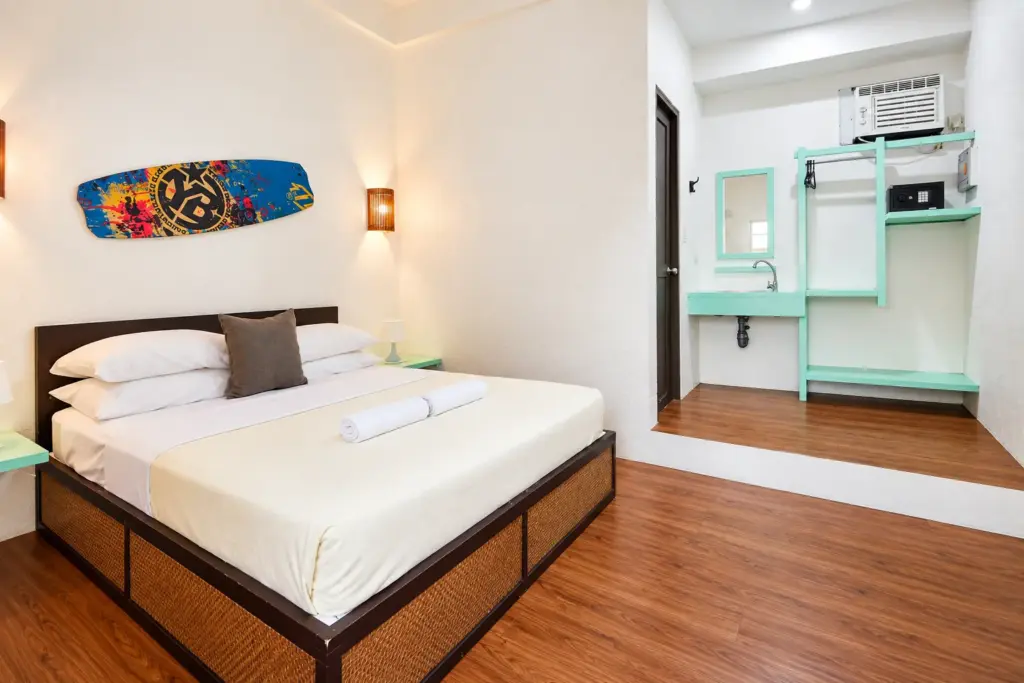 Queen bed with a painted surfboard above it and rattan drawers underneath