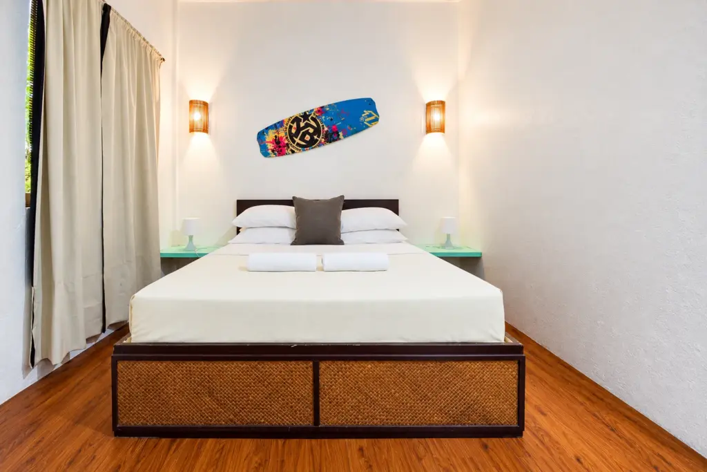Queen bed with surfboard artwork and soft curtains