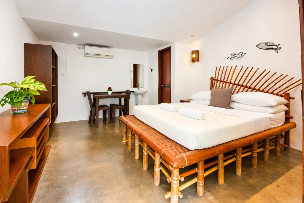 Handcrafted bamboo queen bed with a writing desk and dining table behind