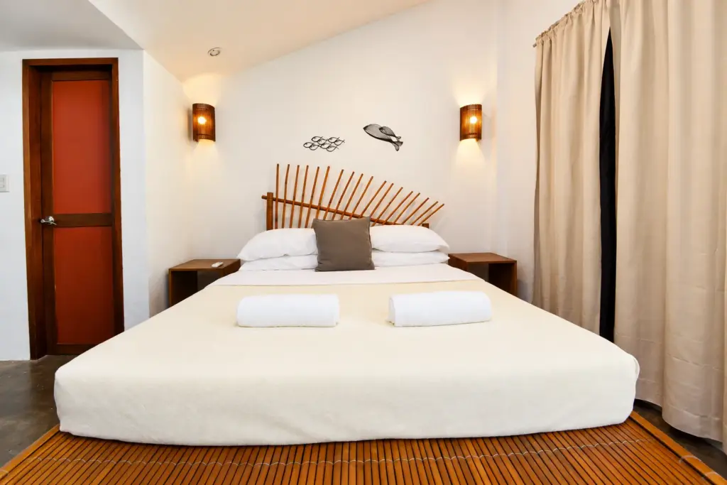 Bamboo queen bed with fish wall art beside a red door