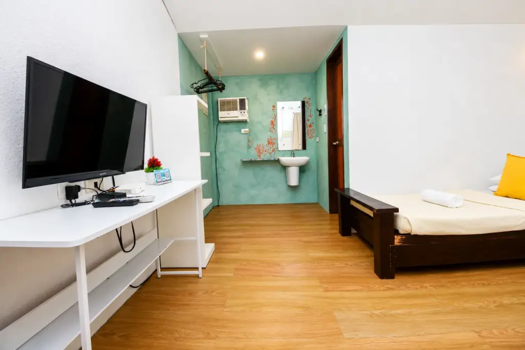 Desk and teal-tiled sink area beside the bed