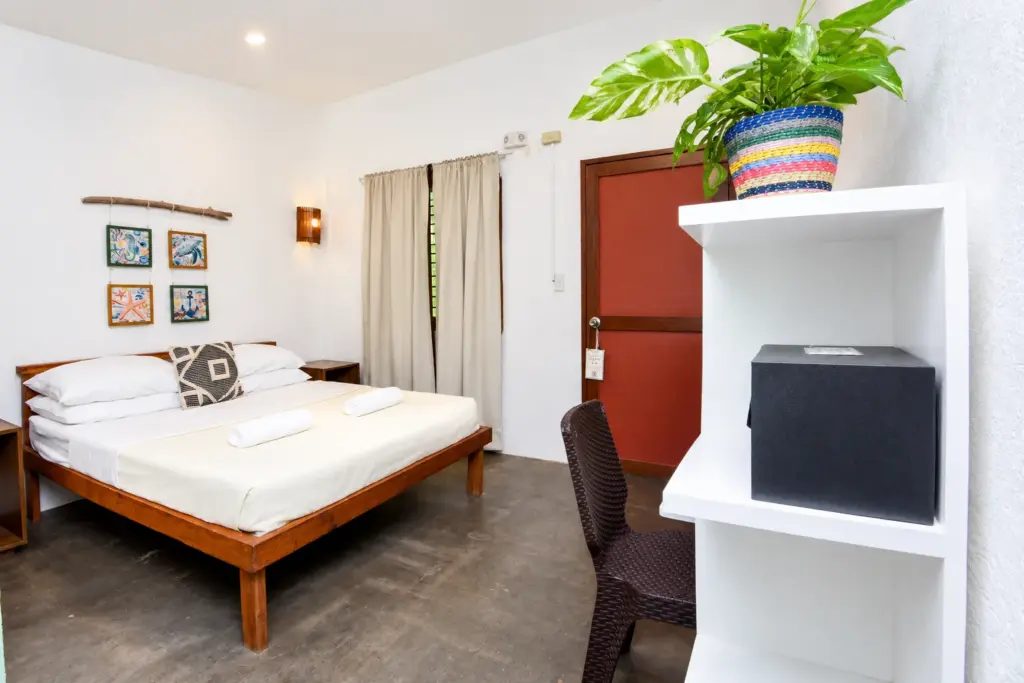 Queen bed with framed prints and an in-room safe on a white shelf
