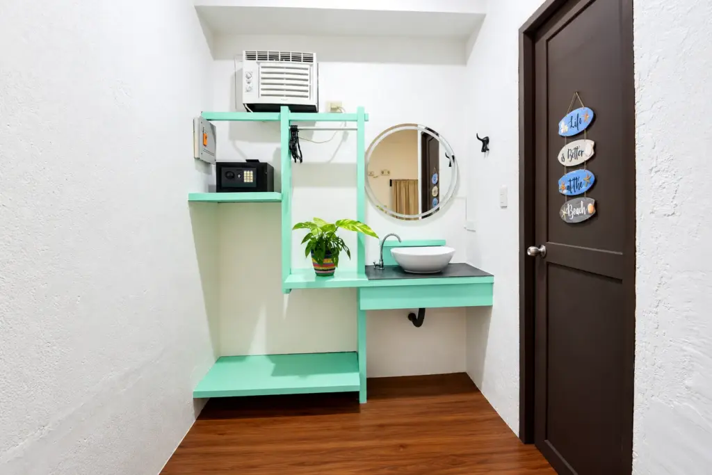 Mint-green vanity with a round mirror beside the room door